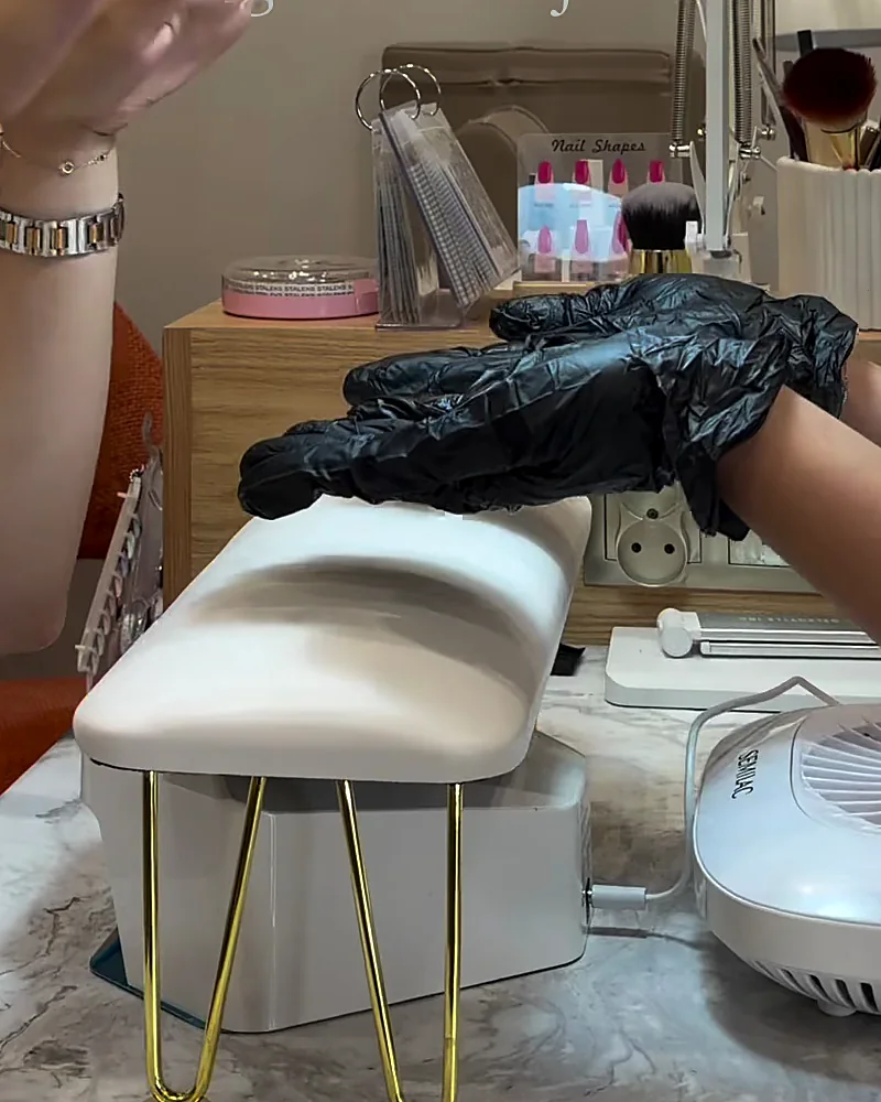 Mains gantées sur le coussin de la table de manucure